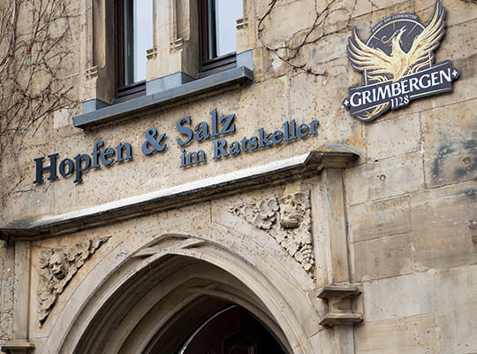 Eingang des Restaurants mit dem Schriftzug Hopfen & Salz im Ratskeller auf der Mauer.
