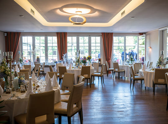 Blick vom Speisesaal durch die großen Fenster in den Gartenbereich des Restaurants.