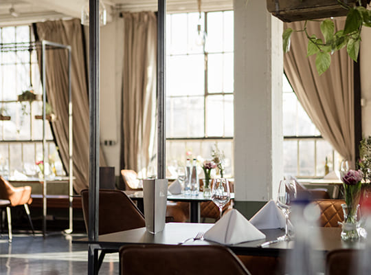 Schön gestalteter Restaurantbereich mit großen Hellen Fenstern und bequemen Sitzmöglichkeiten.