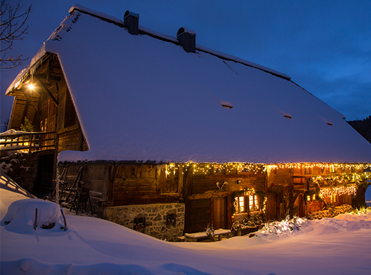 Traumhafte Schneelandschaft und der romantisch beleuchtete Hensler Hof bei Nacht