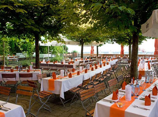 Große Terrasse mit schönem Ausblick und großen langen Esstischgarnituren