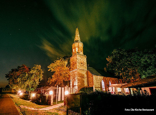 Ein strahlender Nachthimmel vor dem eine alte Kirche thront