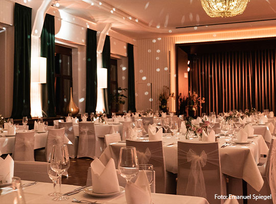 Schöner Saal mit vielen gedeckten Tischen und Bühne für das Krimidinner Mannheim im Bootshaus