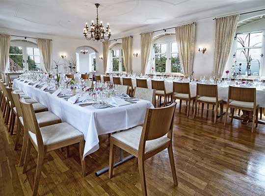 Lange Tafeln und Kronleuchter im Saal des Schloss Weinstein