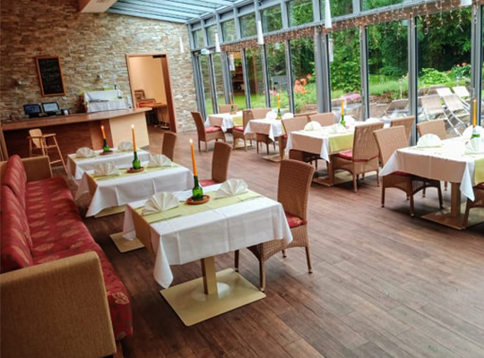 Schöner Wintergarten mit Blick ins Grüne, schön gedeckte Tische in Berger´s Airporthotel Memmingen