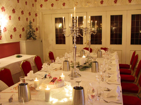Stilvolle Einrichtung mit weißen Tischen, roten Stühlen und silbernen Kerzenständern beim Krimidinner Münster