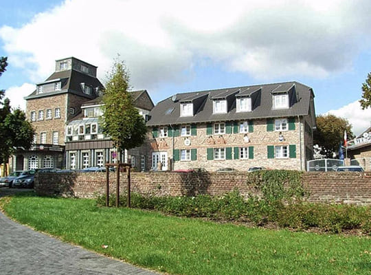 Grüne Wiese inklusive Backsteinmauer vor dem großen Hotel Vintage Gebäude