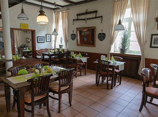 Liebevoll dekorierter Restaurant-Bereich mit hellen Fenstern und gemütlichen Sitzmöglichkeiten.