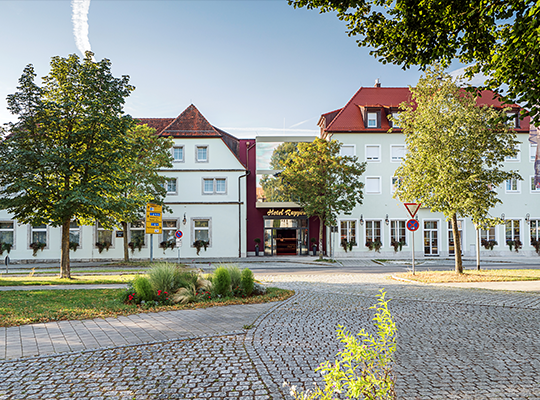 Außenansicht auf das Hotel Rappen mit Bäumen und blauem Himmel