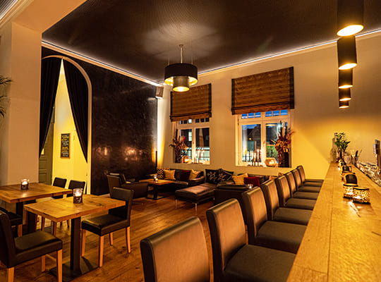 Blick von der Bar-Theke in den noblen Restaurant-Bereich mit vielen Sitzgelegenheiten am Abend.
