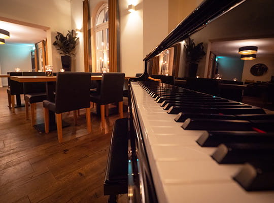 Klavier im Restaurant-Bereich neben den Esstischen sorgt für musikalische Begleitung.