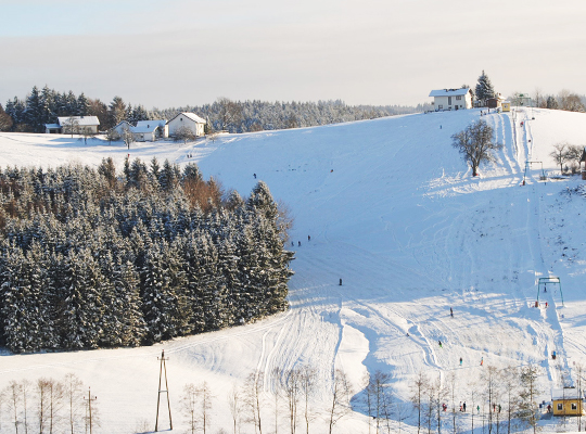 Schneebedeckter Skihang am Liftlokal bei schönstem Sonnenschein im Winter 