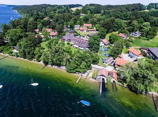 Luftansicht auf das sonnenbestrahlte Hotel direkt am Starnberger See.