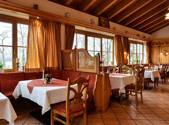 Liebevoll eingerichteter Speisesaal mit großen hellen Fenstern, schöner Tischdeko und vielen gemütlichen Sitzmöglichkeiten.