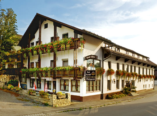 Außenansicht des schönen Landgasthof Gebäudes. Mit schöner Außenterrasse und vielen Blumen als Balkondekoration.