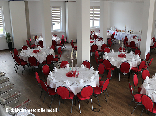 Buffet im großen Speisesaal, in der Mitte befinden sich rote Stühle um runde, weiß gedeckte Tische