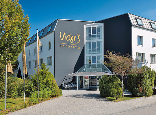 Außenansicht des modernen Victor's Residenz Hotel mit wunderschönem Eingangsbereich aus Glas