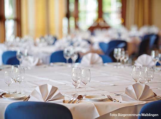 Gedeckter Tisch mit blauen Stühle, weißen Servietten und Gläsern beim