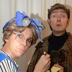 Eine Frau mit blauer Schleife im Haar und ein Mann mit Hut schauen konzentriert. 
