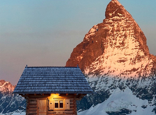 Sonnige Sicht auf einen Berggipfel mit einer Holzhütte davor