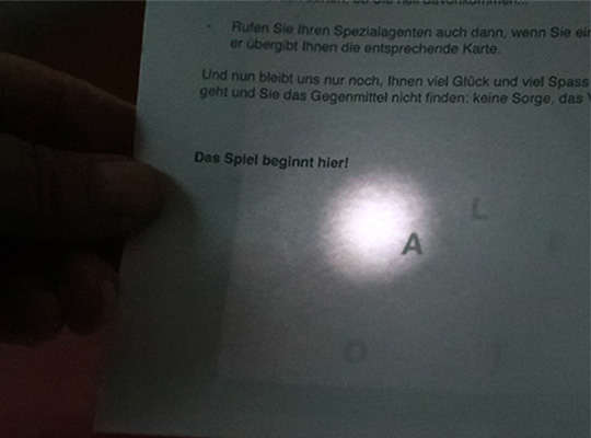 Lampe leuchtet durch Blatt und macht versteckte Buchstaben erkennbar