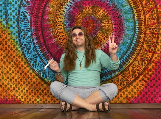 Hippie vor buntem Hintergrund mit Joint in der Hand
