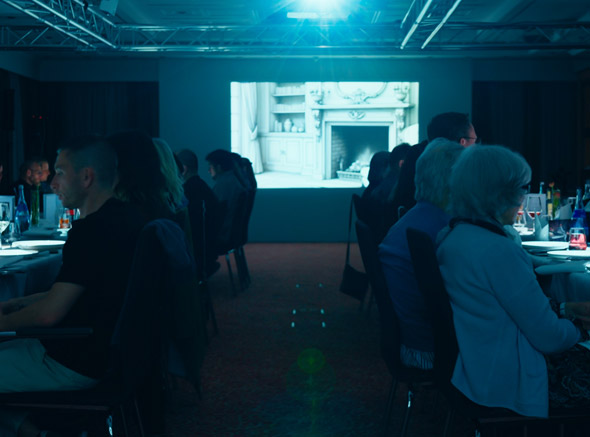Großer Saal mit zwei Tischen und Leinwand 