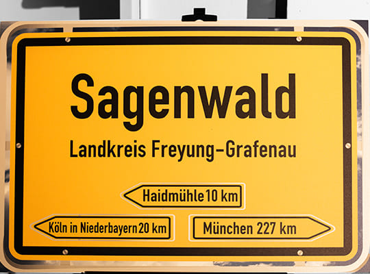 Gelbes Ortsschild mit der Aufschrift: Sagenwald Landkreis Freyung-Grafenau
