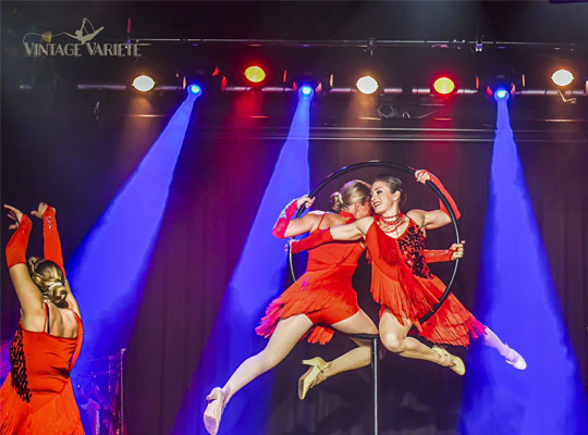 Zwei Darstellerinne in einem von der Decke hängenden Ring