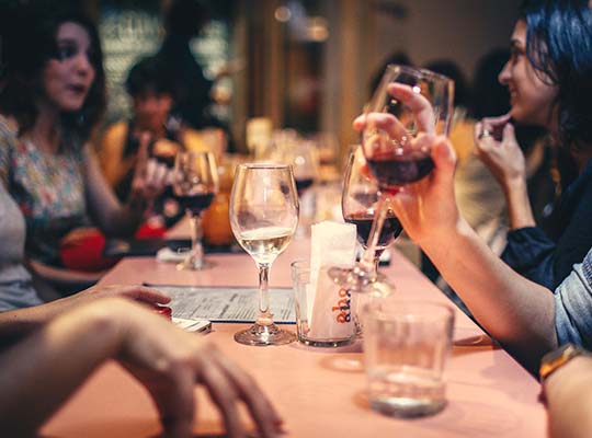 Kollegen sitzen gemeinsam am Tisch und genießen den Wein, sowie das unvergessliche Krimidinner.